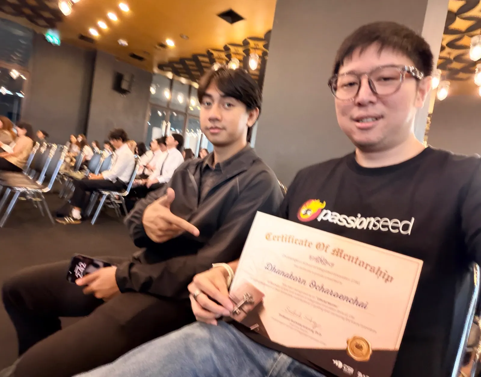 Members seated at a ceremony holding a mentorship certificate